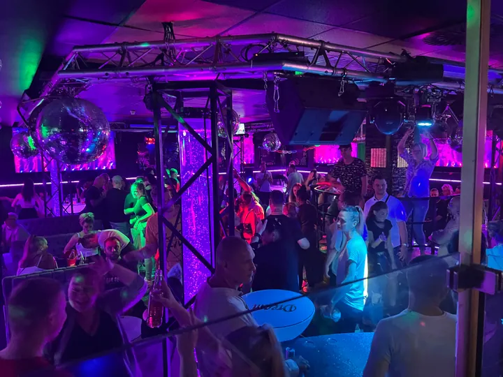 Gäste feiern in einem Club unter violetter Beleuchtung