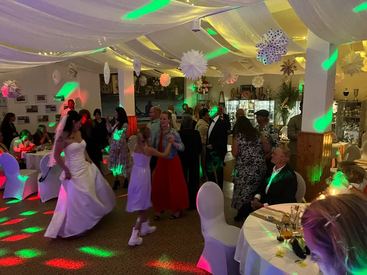 Hochzeitsgesellschaft mit Braut auf der bunt beleuchteten Tanzfläche