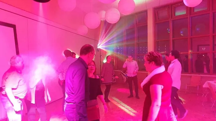 Feiernde Gäste in magentafarbenem Partylicht