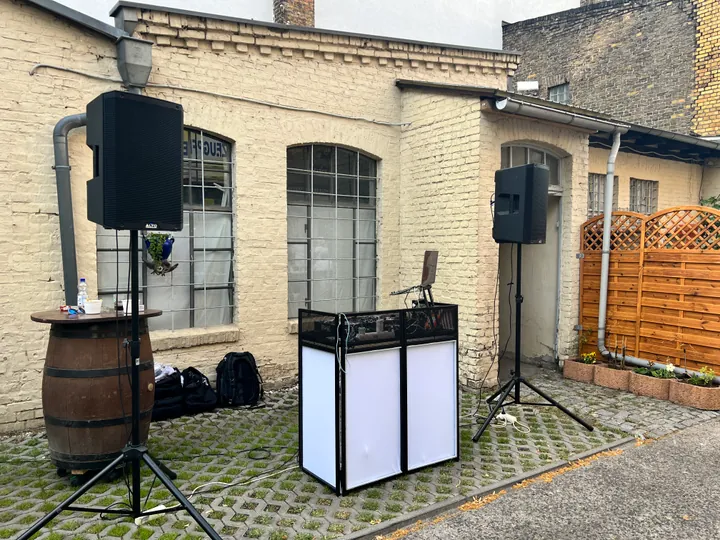 DJ-Pult und Lautsprecher in einem Innenhof vor einer Backsteinfassade