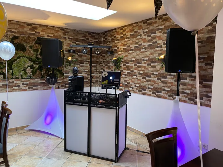Weißes DJ-Pult und Lautsprecher vor einer rustikalen Steinwand