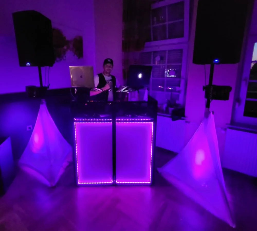 DJ-Setup mit violett beleuchteten Traversen und Lautsprechern